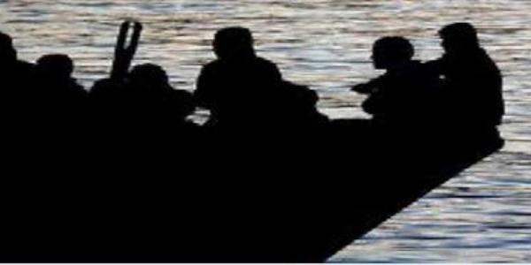 A photograph showing a silhouetted image of a boat carrying a large number of people across a body of water.